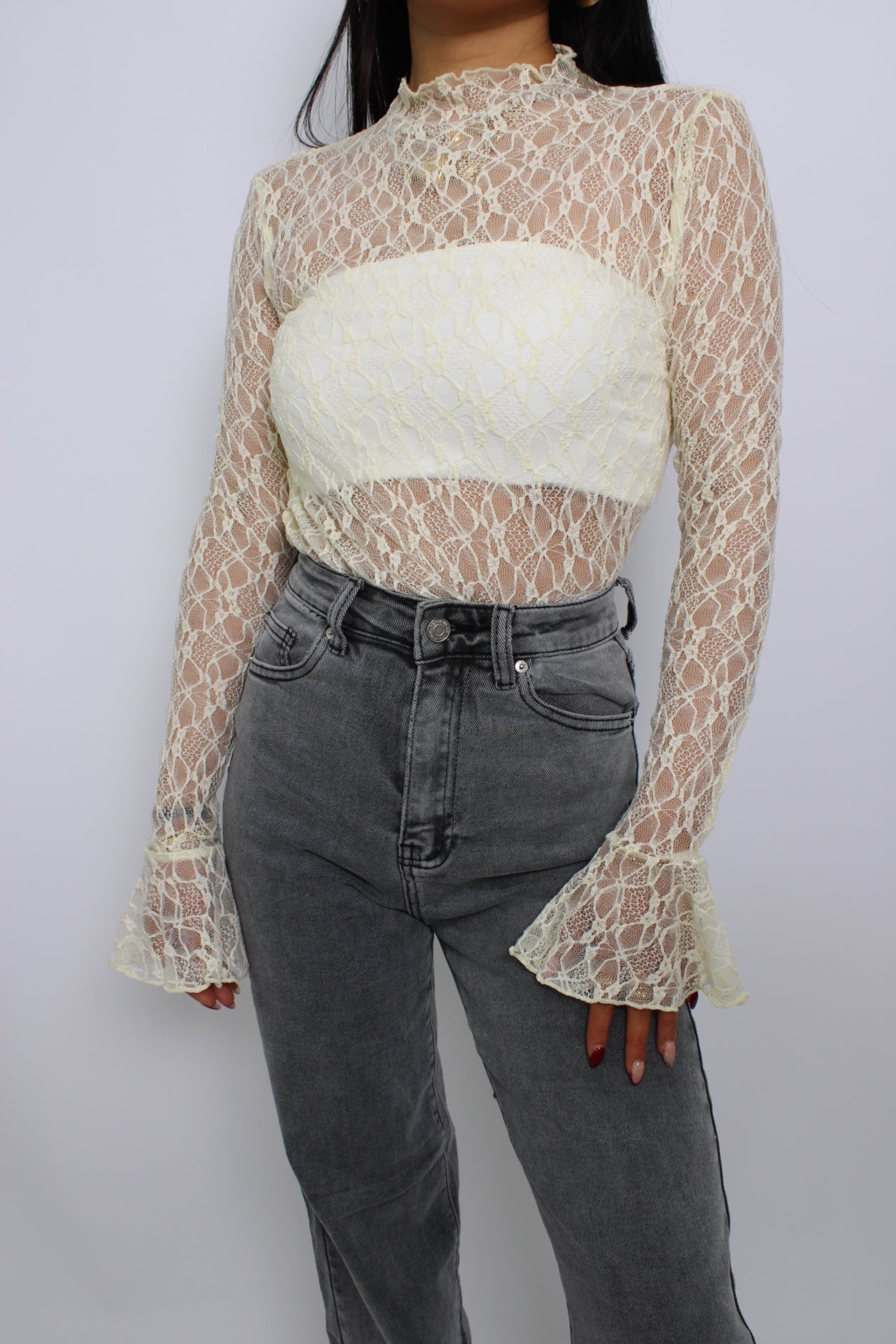 Een elegante kanten top met flare mouwen, een losse pasvorm en een verfijnde uitstraling. De top heeft een ronde halslijn en een delicate, doorzichtige stof voor een vrouwelijke look.