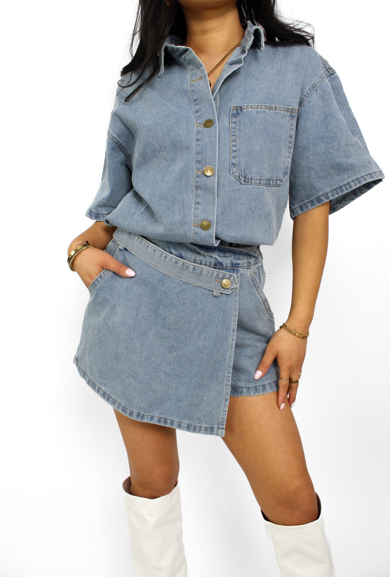 Een trendy denim 2-delig setje bestaande uit een korte top met knoopsluiting en een bijpassende skort. De skort heeft een A-lijn pasvorm met een subtiele rits aan de zijkant en een casual, veelzijdige uitstraling, perfect voor een zomerse look.