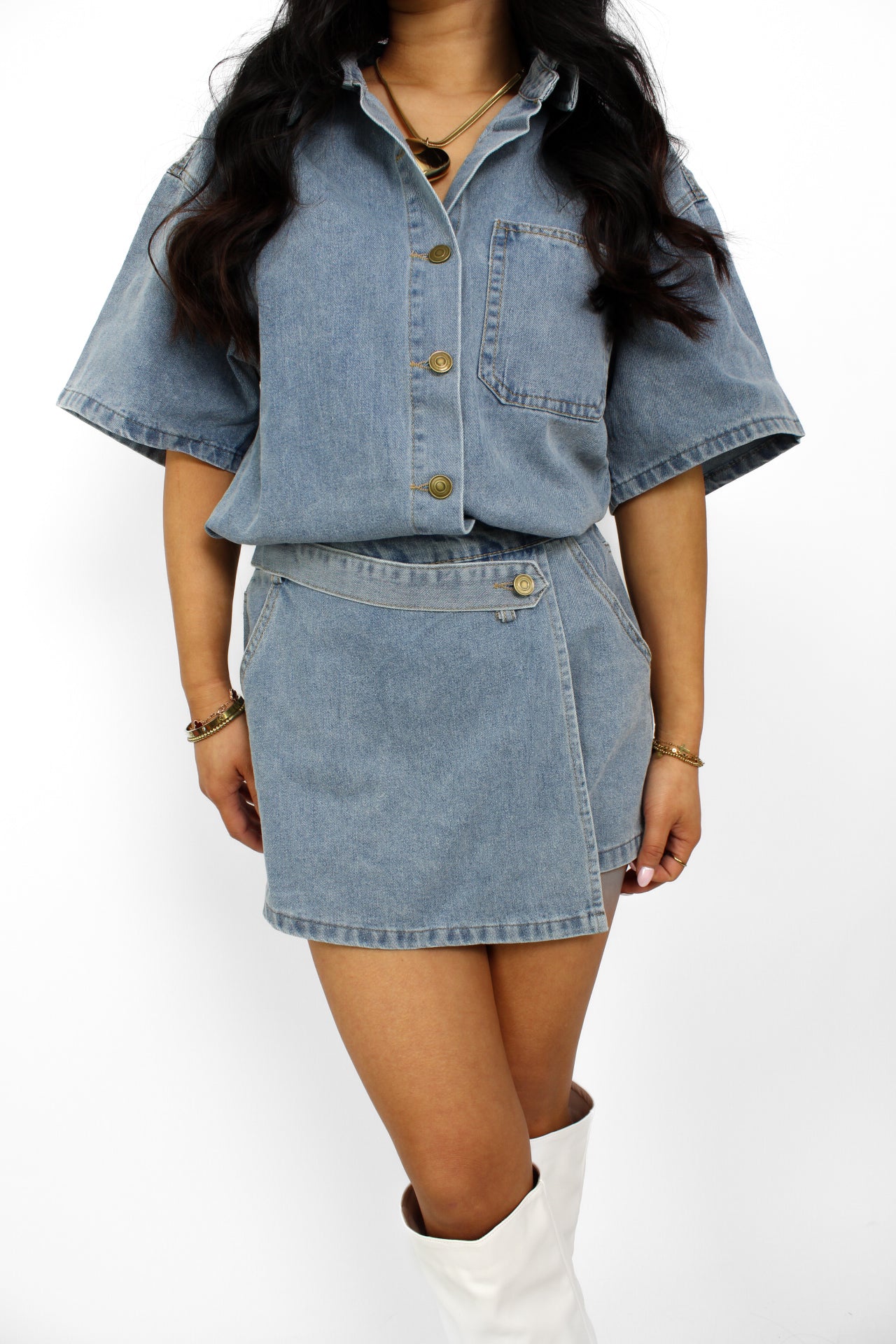 Een trendy denim 2-delig setje bestaande uit een korte top met knoopsluiting en een bijpassende skort. De skort heeft een A-lijn pasvorm met een subtiele rits aan de zijkant en een casual, veelzijdige uitstraling, perfect voor een zomerse look.