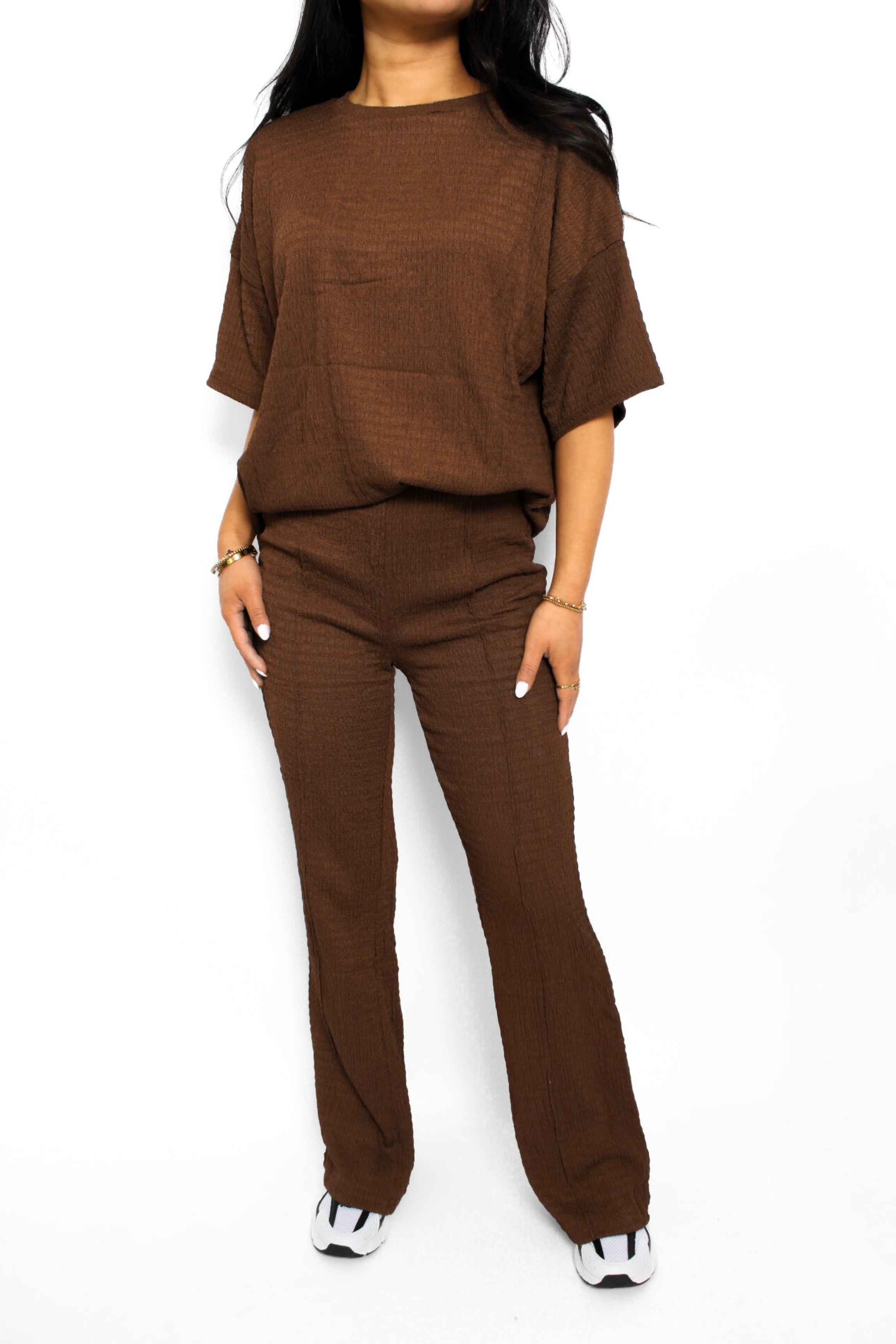 Een stijlvolle en luchtige 2-delige set bestaande uit een lichtgewicht top en een bijpassende broek. De top heeft een ontspannen pasvorm met korte mouwen en een subtiele ronde hals, terwijl de broek een comfortabele elastische tailleband heeft en soepel valt voor een casual look. Perfect voor warme dagen en een moeiteloze, frisse uitstraling.