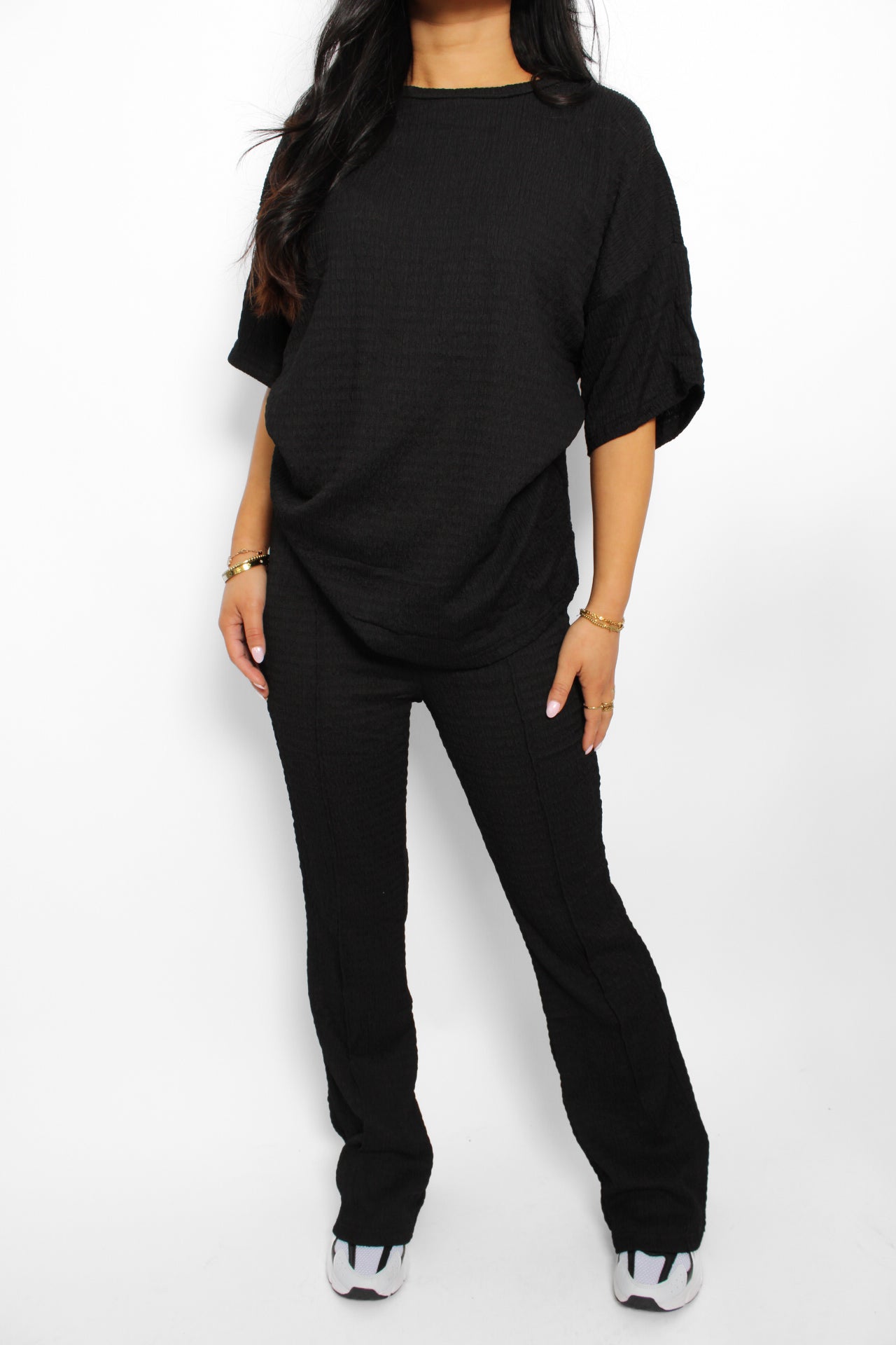 Een stijlvolle en luchtige 2-delige set bestaande uit een lichtgewicht top en een bijpassende broek. De top heeft een ontspannen pasvorm met korte mouwen en een subtiele ronde hals, terwijl de broek een comfortabele elastische tailleband heeft en soepel valt voor een casual look. Perfect voor warme dagen en een moeiteloze, frisse uitstraling
