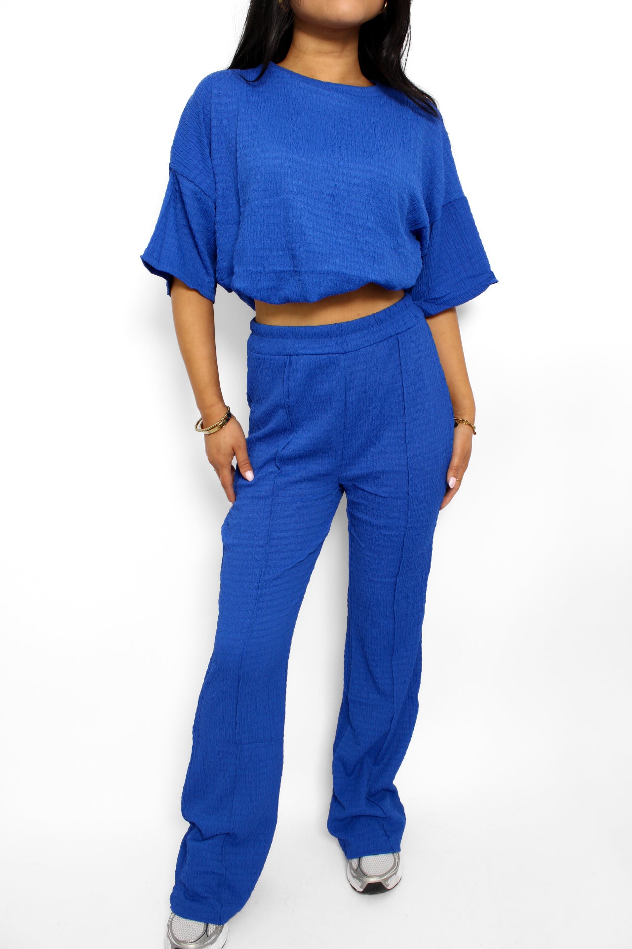 Een stijlvolle en luchtige 2-delige set bestaande uit een lichtgewicht top en een bijpassende broek. De top heeft een ontspannen pasvorm met korte mouwen en een subtiele ronde hals, terwijl de broek een comfortabele elastische tailleband heeft en soepel valt voor een casual look. Perfect voor warme dagen en een moeiteloze, frisse uitstraling