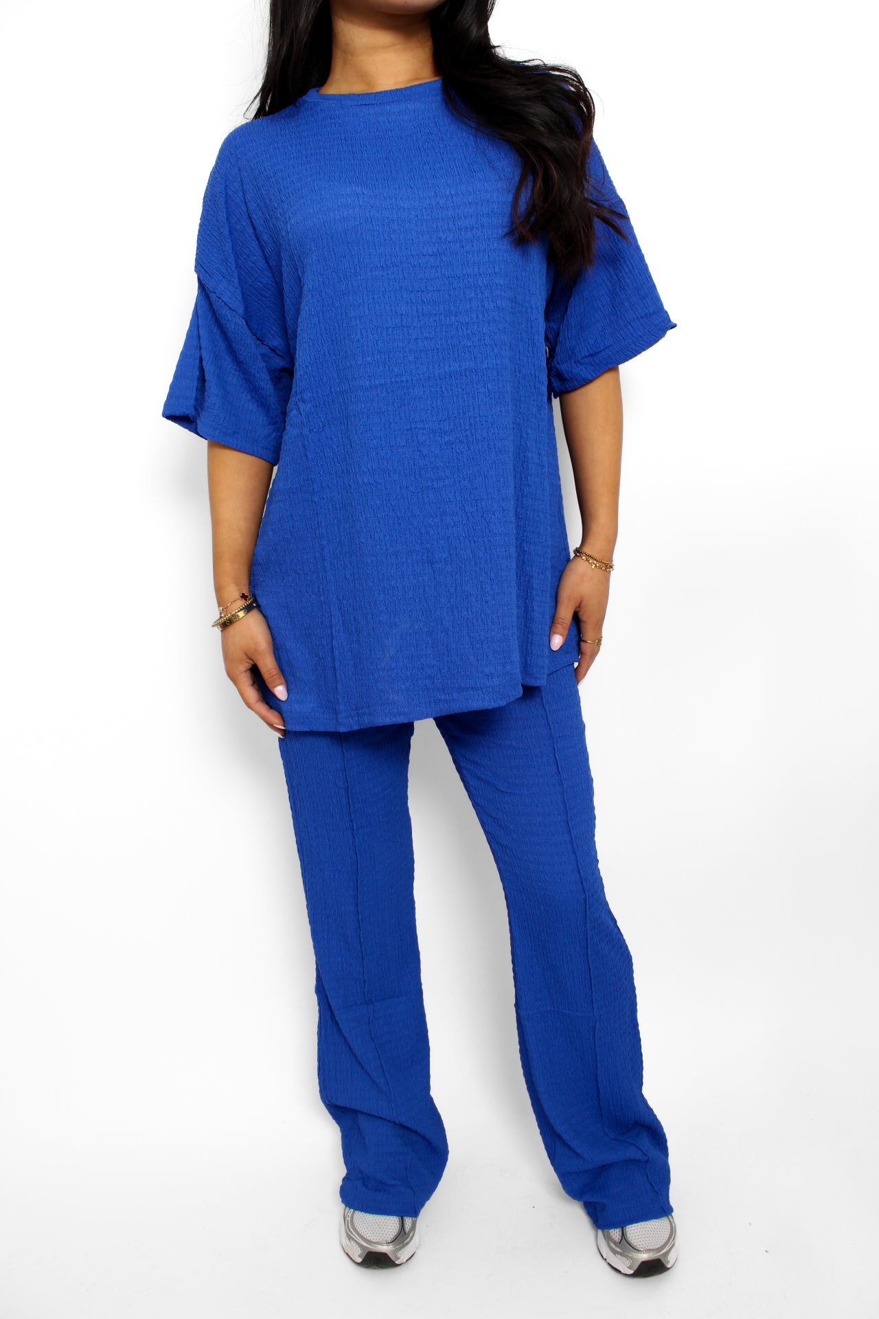 Een stijlvolle en luchtige 2-delige set bestaande uit een lichtgewicht top en een bijpassende broek. De top heeft een ontspannen pasvorm met korte mouwen en een subtiele ronde hals, terwijl de broek een comfortabele elastische tailleband heeft en soepel valt voor een casual look. Perfect voor warme dagen en een moeiteloze, frisse uitstraling