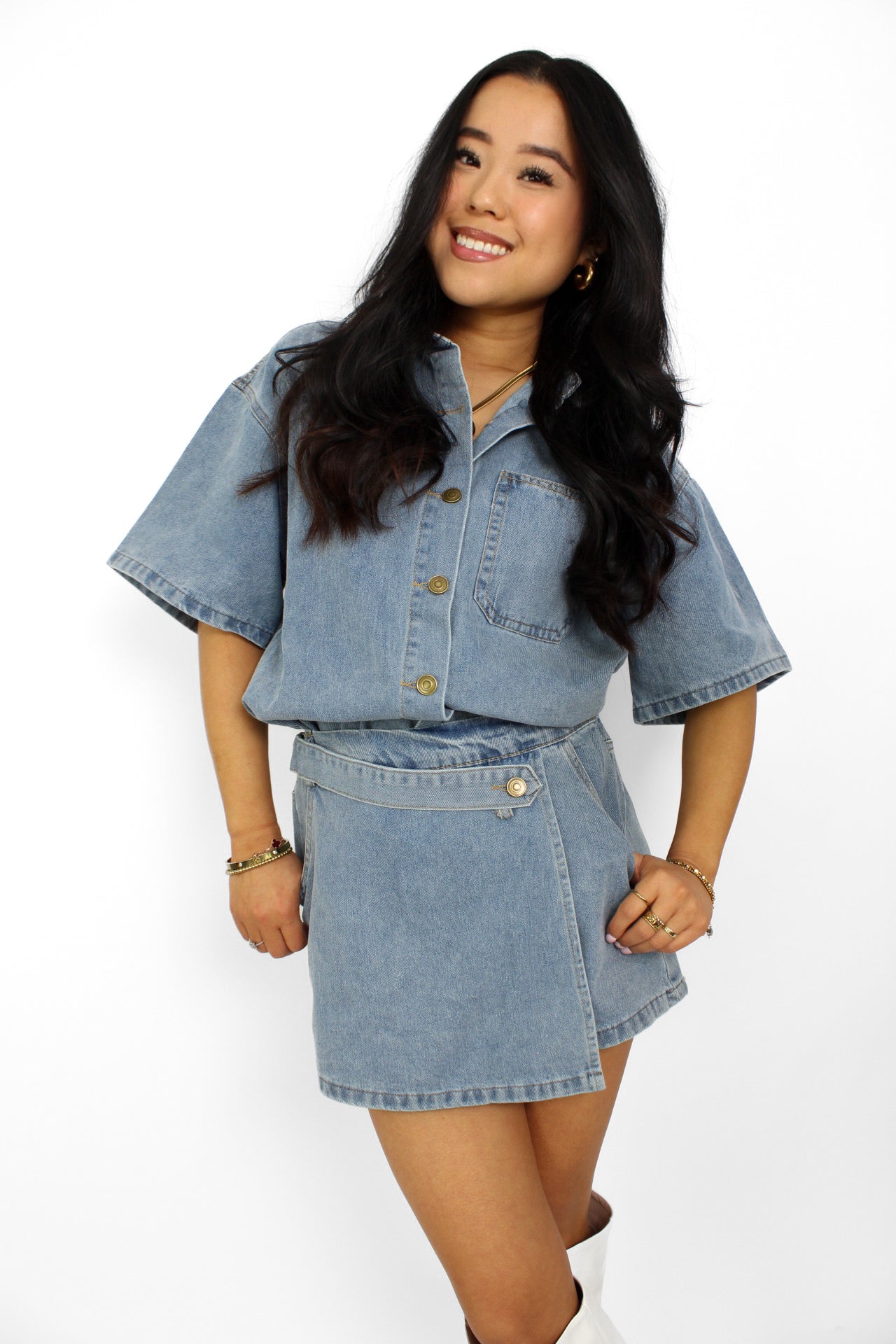 Een trendy denim 2-delig setje bestaande uit een korte top met knoopsluiting en een bijpassende skort. De skort heeft een A-lijn pasvorm met een subtiele rits aan de zijkant en een casual, veelzijdige uitstraling, perfect voor een zomerse look.