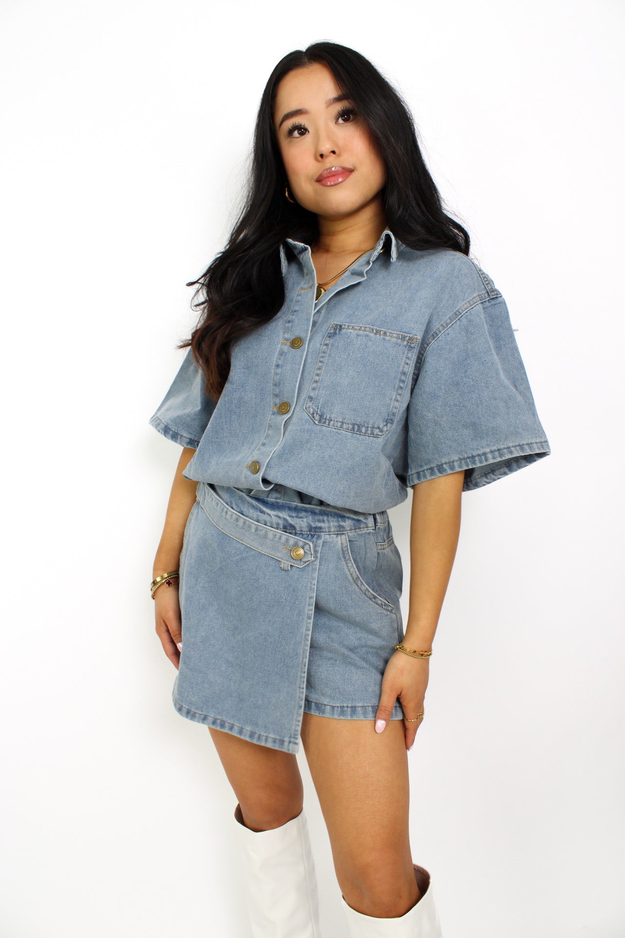 Een trendy denim 2-delig setje bestaande uit een korte top met knoopsluiting en een bijpassende skort. De skort heeft een A-lijn pasvorm met een subtiele rits aan de zijkant en een casual, veelzijdige uitstraling, perfect voor een zomerse look.