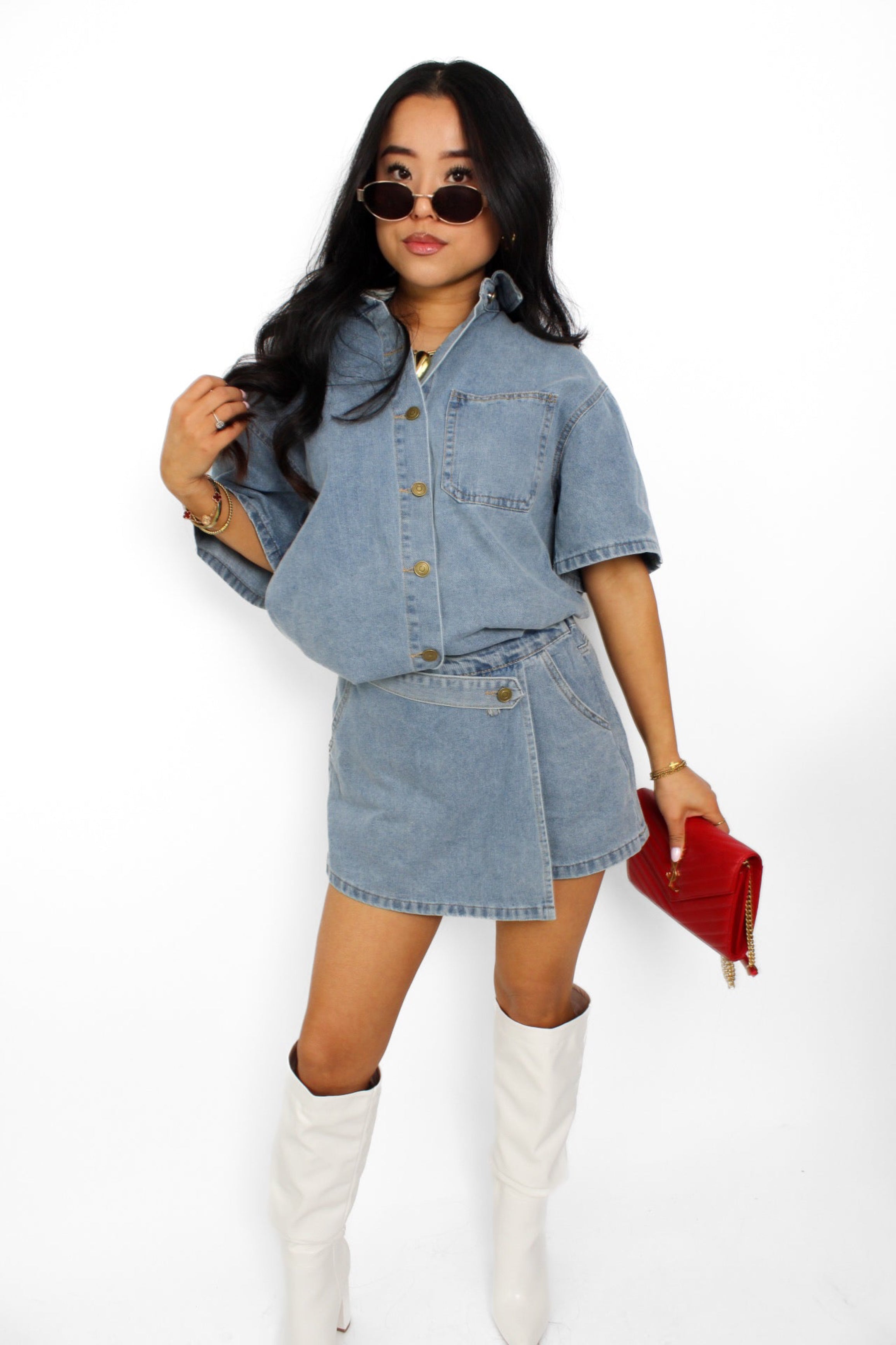 Een trendy denim 2-delig setje bestaande uit een korte top met knoopsluiting en een bijpassende skort. De skort heeft een A-lijn pasvorm met een subtiele rits aan de zijkant en een casual, veelzijdige uitstraling, perfect voor een zomerse look.