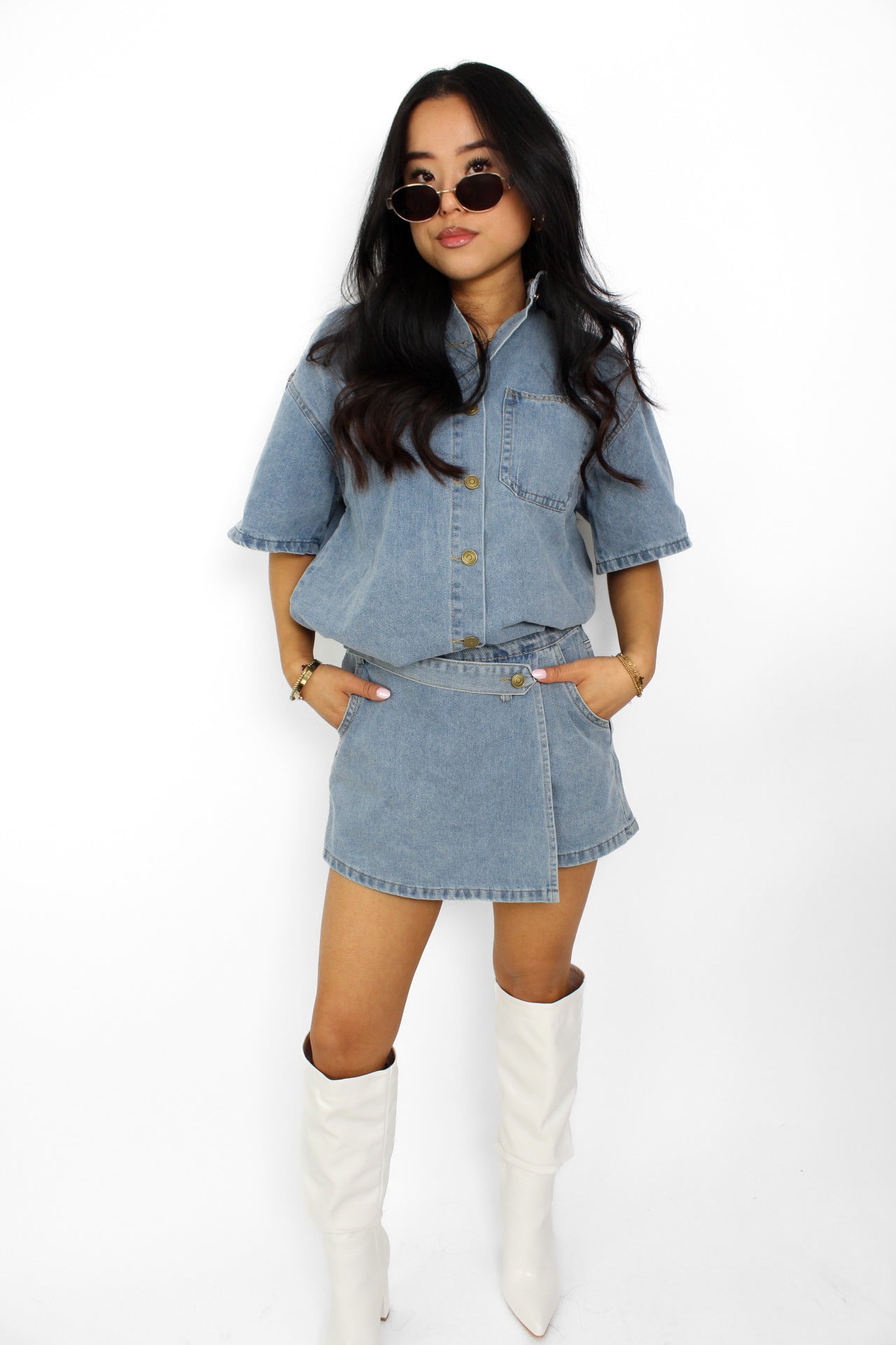 Een trendy denim 2-delig setje bestaande uit een korte top met knoopsluiting en een bijpassende skort. De skort heeft een A-lijn pasvorm met een subtiele rits aan de zijkant en een casual, veelzijdige uitstraling, perfect voor een zomerse look.