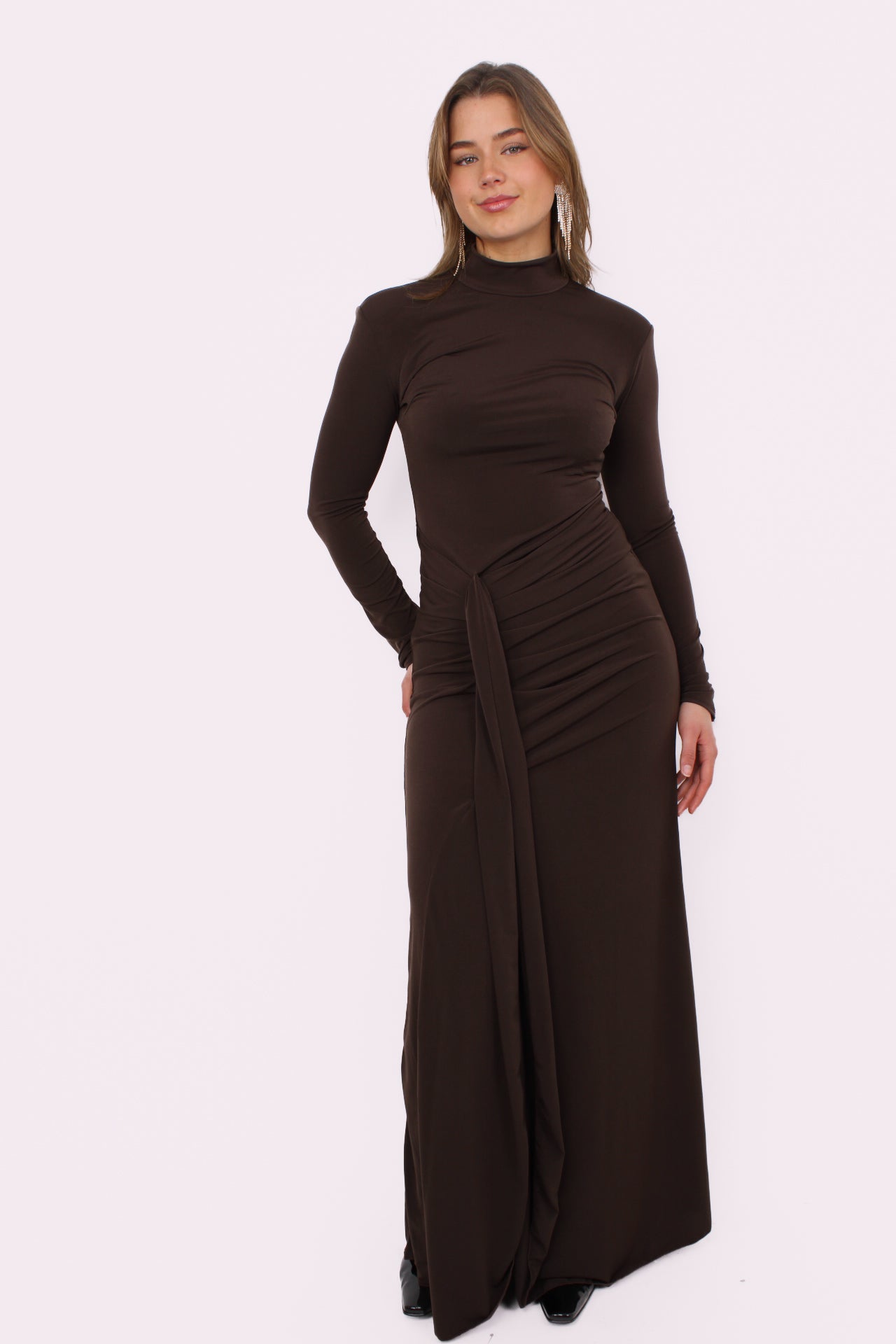 Deze prachtige maxi jurk heeft een speelse split aan je rechterbeen, waardoor hij meteen iets flirterigs krijgt. De iets hogere halslijn geeft ’m net dat stijlvolle randje, terwijl de gedrapeerde taille je figuur mooi volgt zonder strak te zitten. De stof valt soepel en geeft de jurk een romantische, effortless vibe.