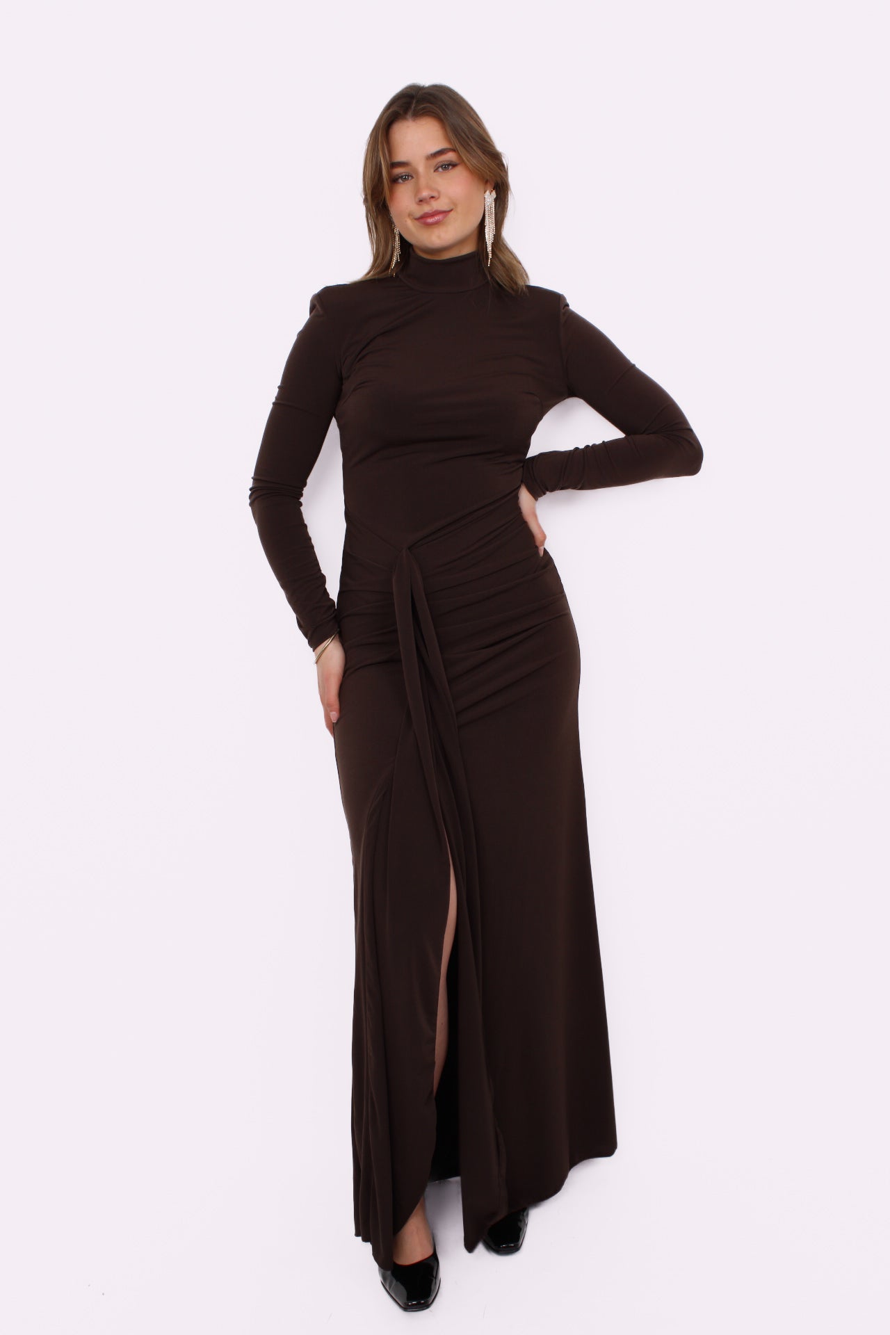 Deze prachtige maxi jurk heeft een speelse split aan je rechterbeen, waardoor hij meteen iets flirterigs krijgt. De iets hogere halslijn geeft ’m net dat stijlvolle randje, terwijl de gedrapeerde taille je figuur mooi volgt zonder strak te zitten. De stof valt soepel en geeft de jurk een romantische, effortless vibe.