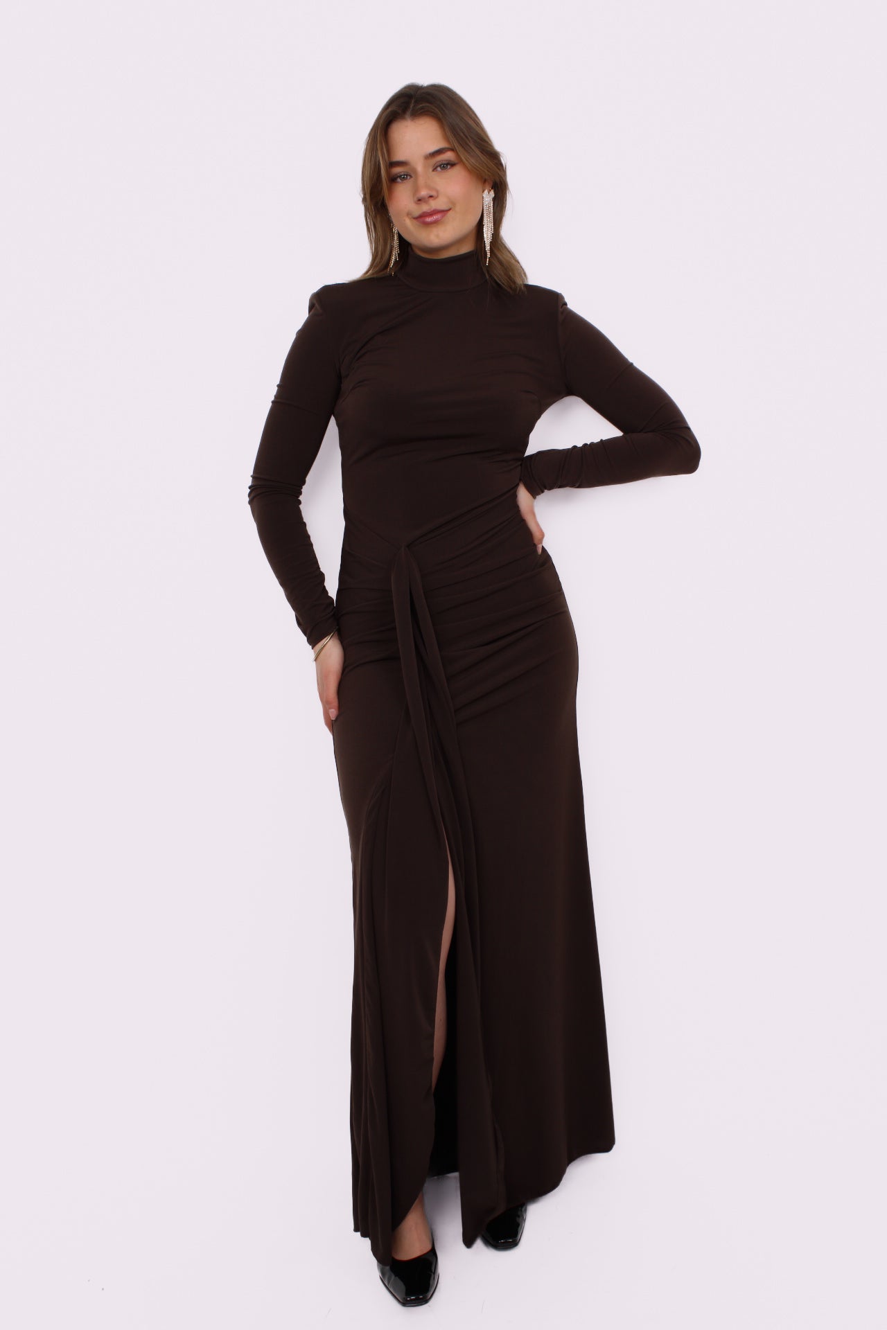 Deze prachtige maxi jurk heeft een speelse split aan je rechterbeen, waardoor hij meteen iets flirterigs krijgt. De iets hogere halslijn geeft ’m net dat stijlvolle randje, terwijl de gedrapeerde taille je figuur mooi volgt zonder strak te zitten. De stof valt soepel en geeft de jurk een romantische, effortless vibe.