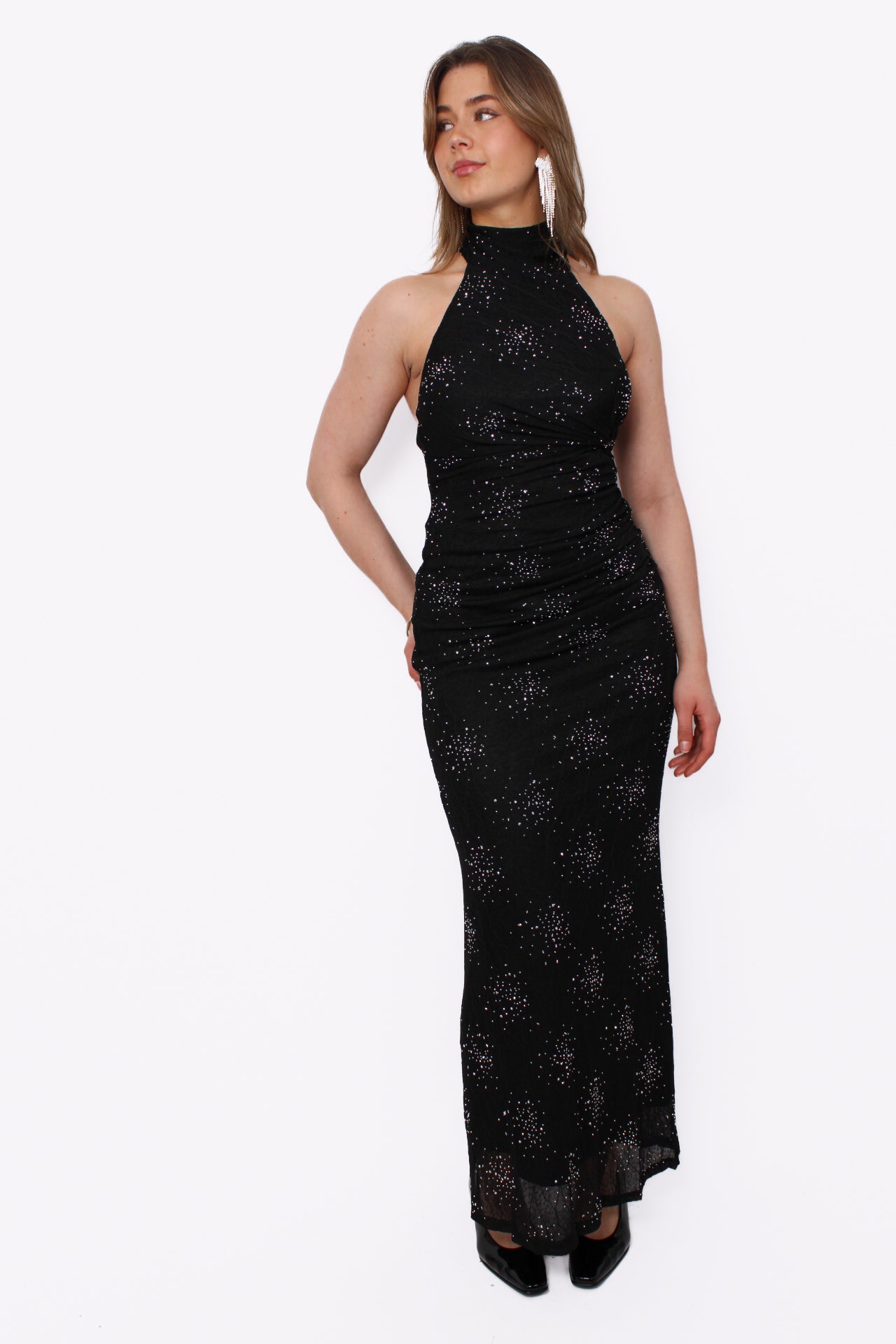 zwarte, glinsterende maxi halterjurk met plooidetails en een open rug