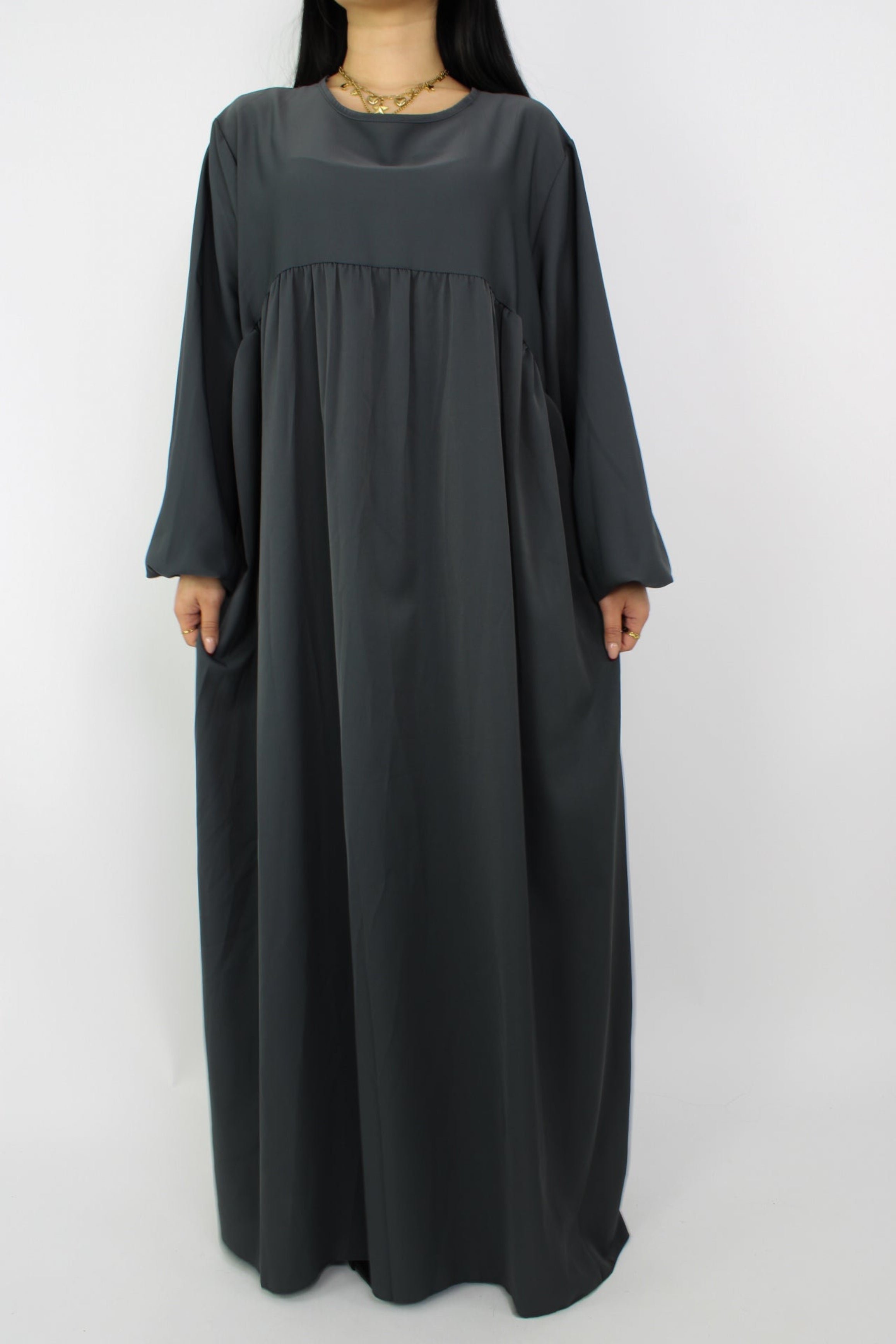 Stijlvolle, lange jurk met een losse pasvorm, ontworpen om comfortabel te dragen met een hijab, met een bescheiden halslijn en mouwen. Satijnen abaya