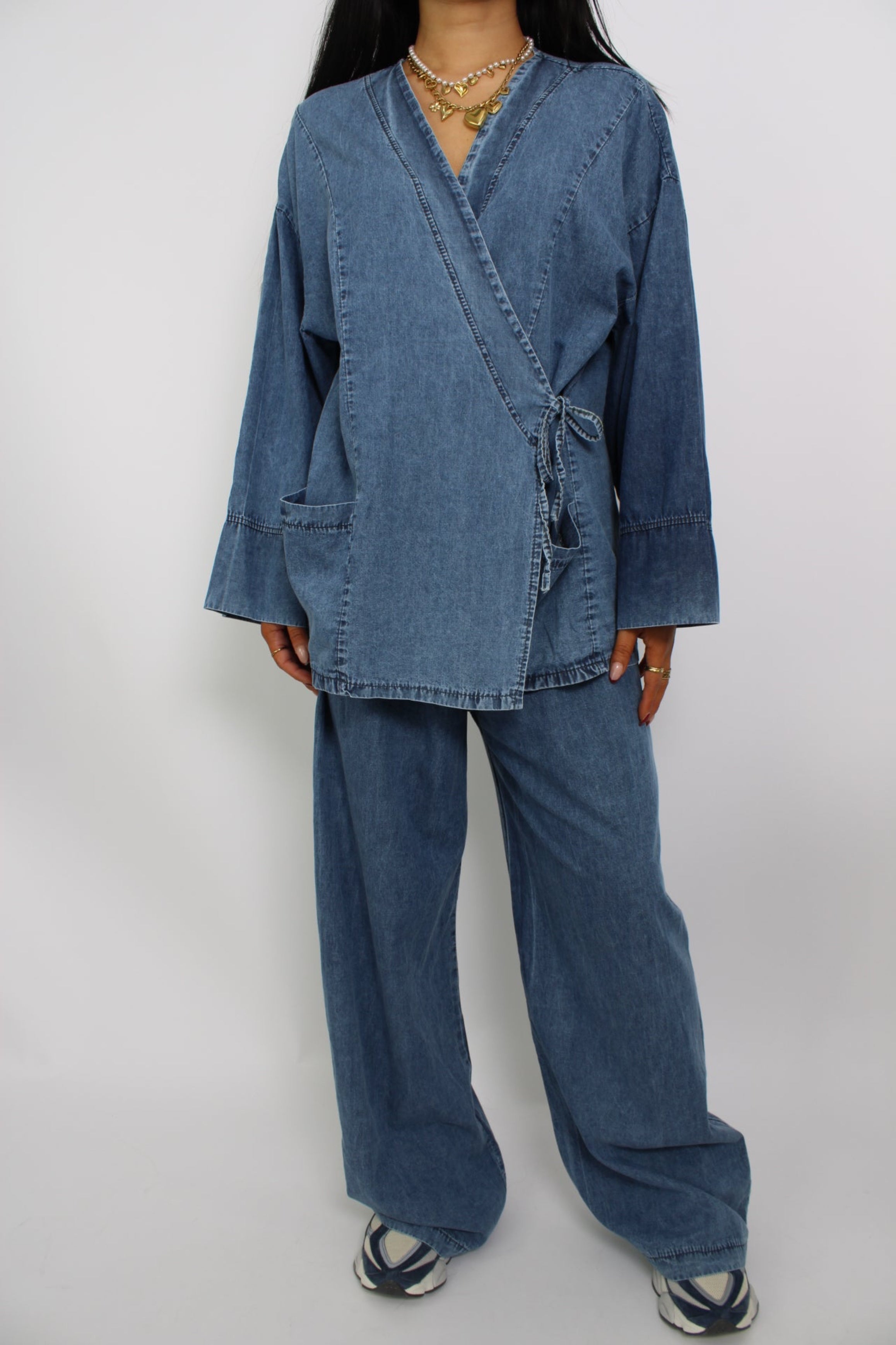Een twee-delige set van spijkerstof, bestaande uit een spijkerblouse en bijpassende spijkerbroek. De set heeft een casual, moderne pasvorm voor een stijlvolle en comfortabele look.
