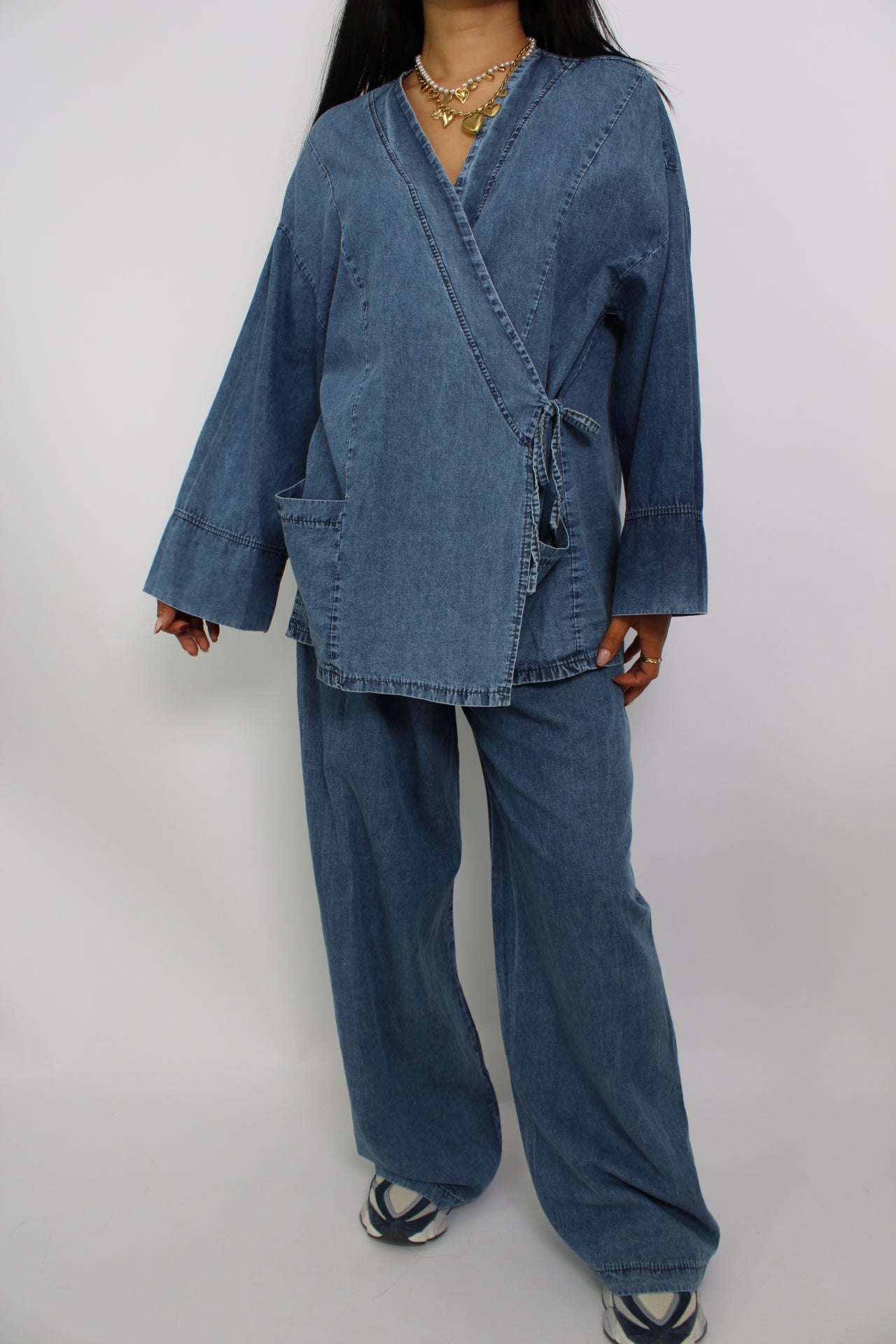 Een twee-delige set van spijkerstof, bestaande uit een spijkerblouse en bijpassende spijkerbroek. De set heeft een casual, moderne pasvorm voor een stijlvolle en comfortabele look.