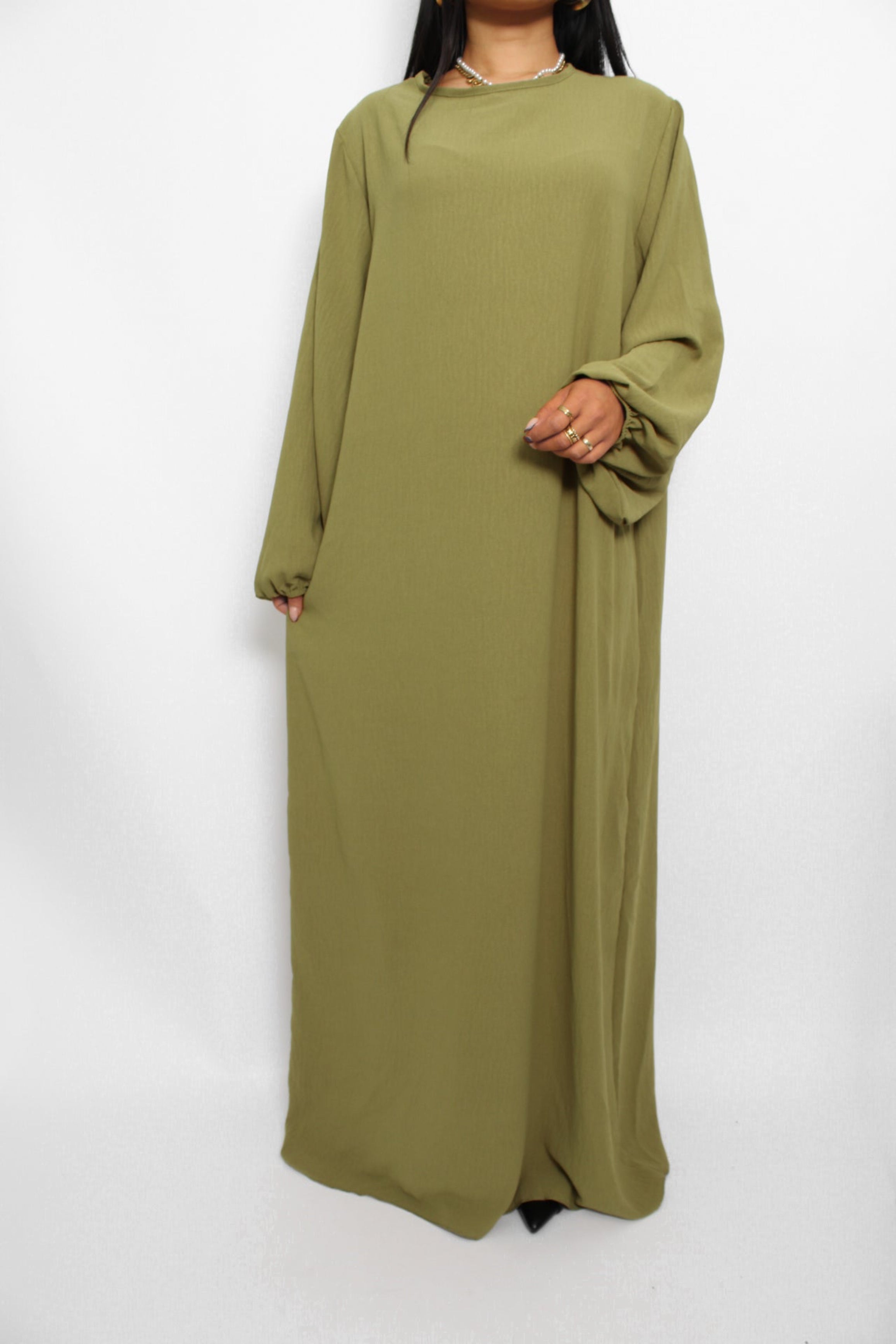 Een basic abaya jurk met een losse pasvorm, lange mouwen en een hoge halslijn. Gemaakt van ademende, niet-doorzichtige stof voor een comfortabele en stijlvolle look."