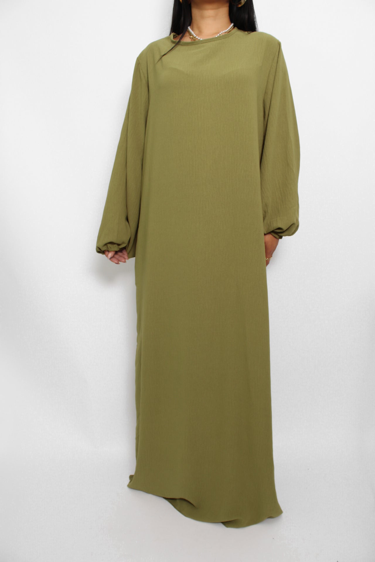Een basic abaya jurk met een losse pasvorm, lange mouwen en een hoge halslijn. Gemaakt van ademende, niet-doorzichtige stof voor een comfortabele en stijlvolle look."