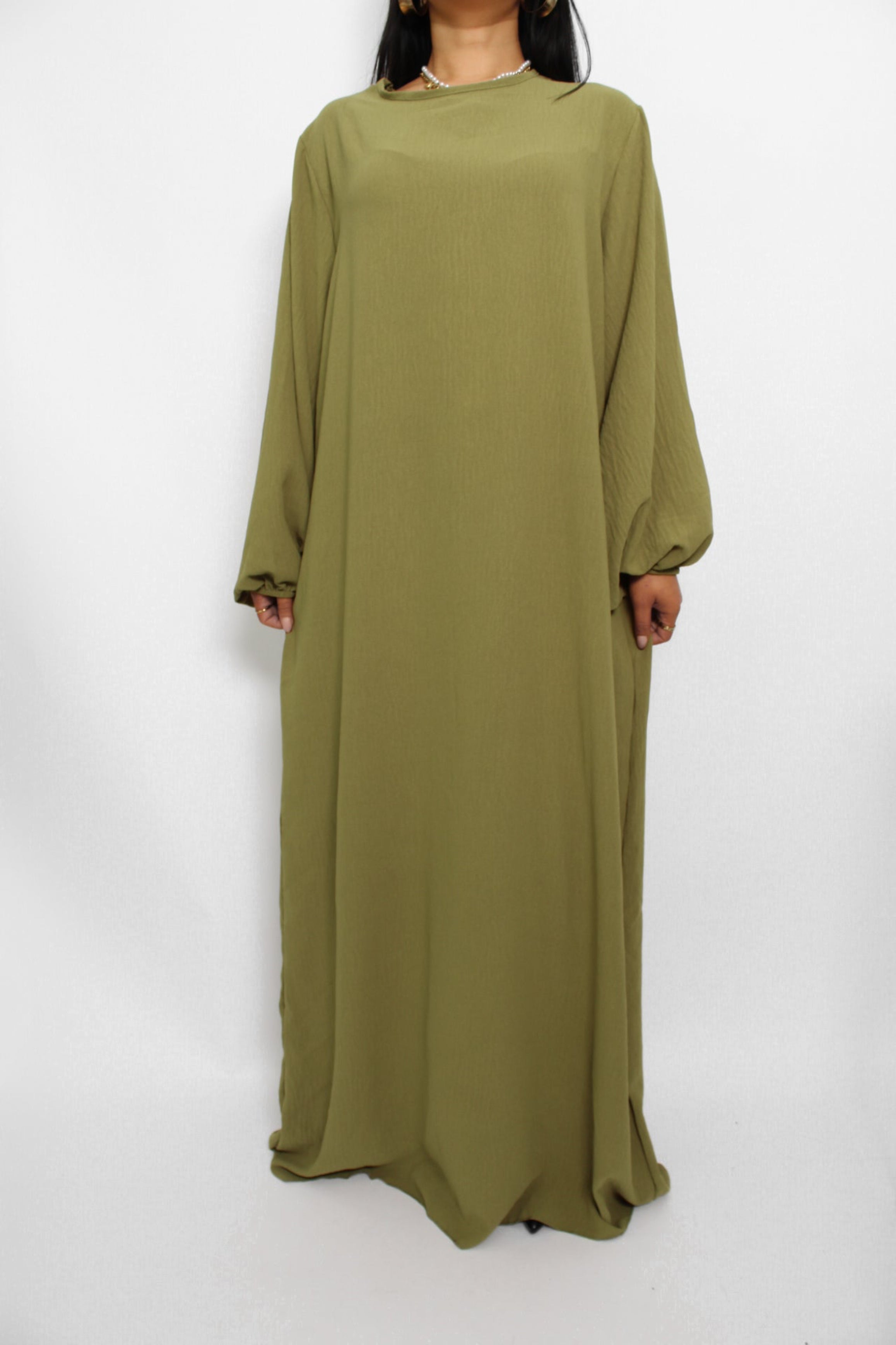 Een basic abaya jurk met een losse pasvorm, lange mouwen en een hoge halslijn. Gemaakt van ademende, niet-doorzichtige stof voor een comfortabele en stijlvolle look."