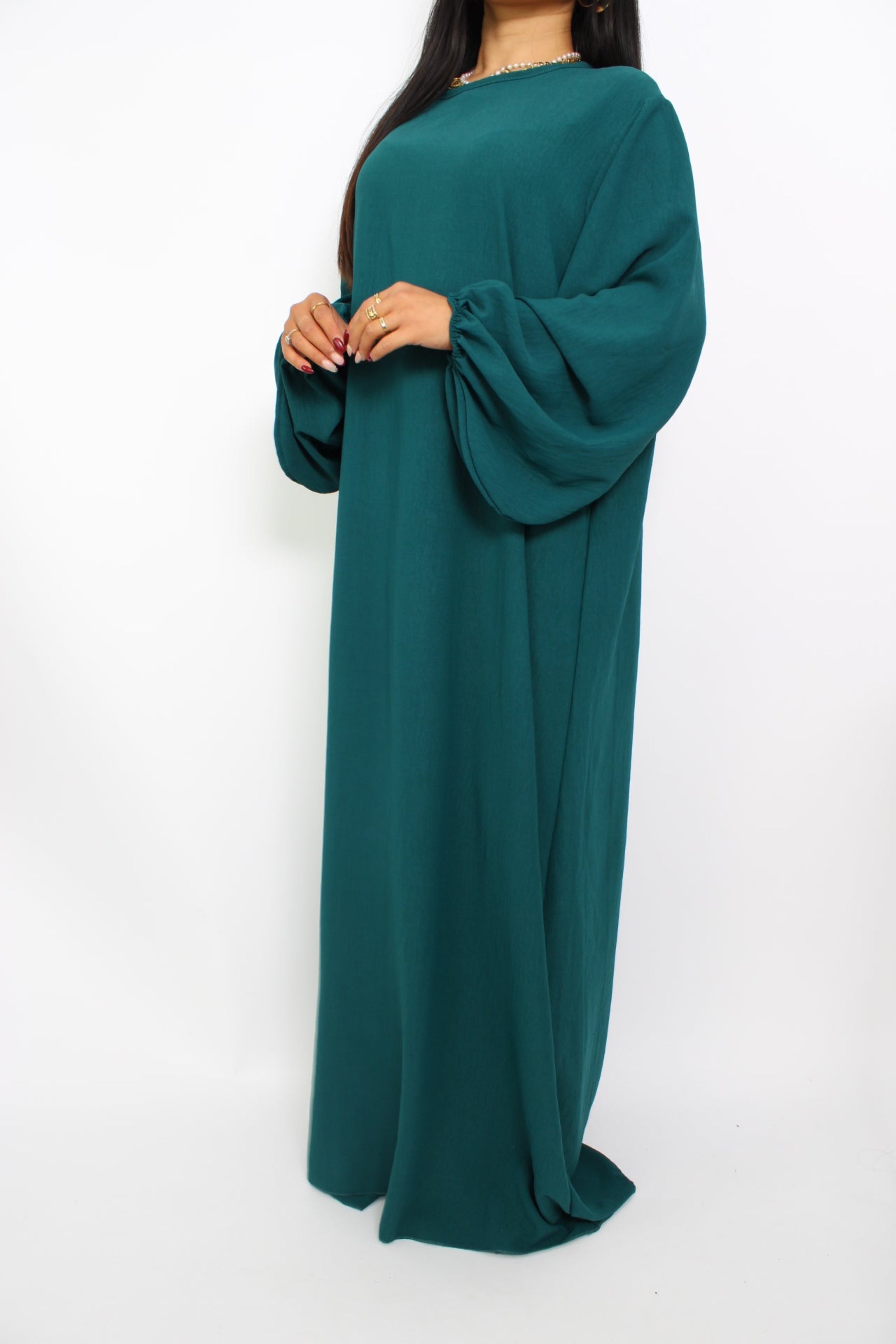 Een basic abaya jurk met een losse pasvorm, lange mouwen en een hoge halslijn. Gemaakt van ademende, niet-doorzichtige stof voor een comfortabele en stijlvolle look."