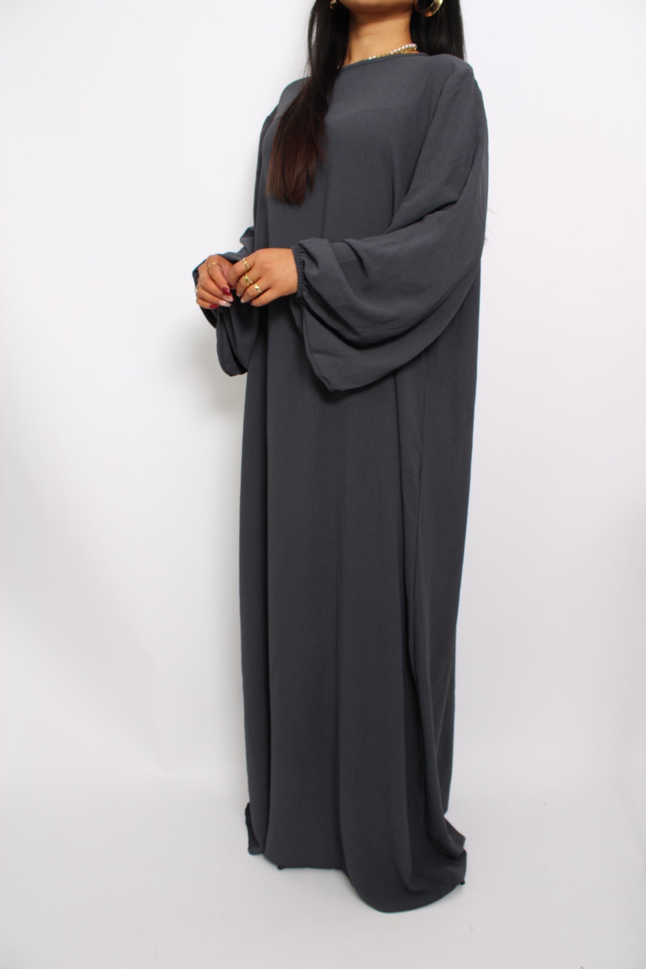 Een basic abaya jurk met een losse pasvorm, lange mouwen en een hoge halslijn. Gemaakt van ademende, niet-doorzichtige stof voor een comfortabele en stijlvolle look."
