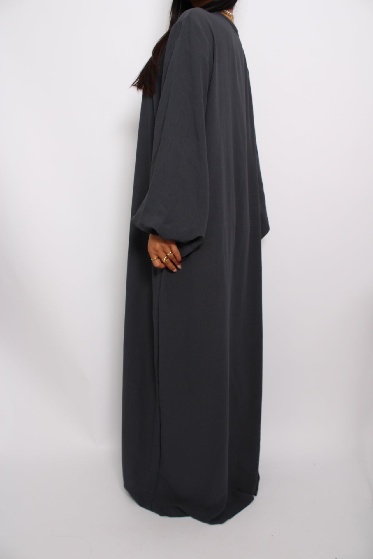 Een basic abaya jurk met een losse pasvorm, lange mouwen en een hoge halslijn. Gemaakt van ademende, niet-doorzichtige stof voor een comfortabele en stijlvolle look."