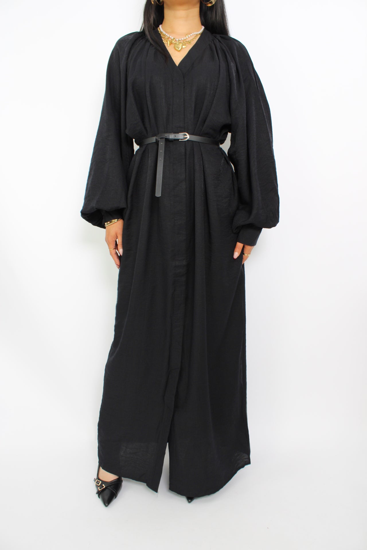 Een modest jurk in zwart, met een losse pasvorm, lange mouwen, een hoge halslijn en een bijpassende ceintuur. Gemaakt van ademende, niet-doorzichtige stof voor comfort en stijl.