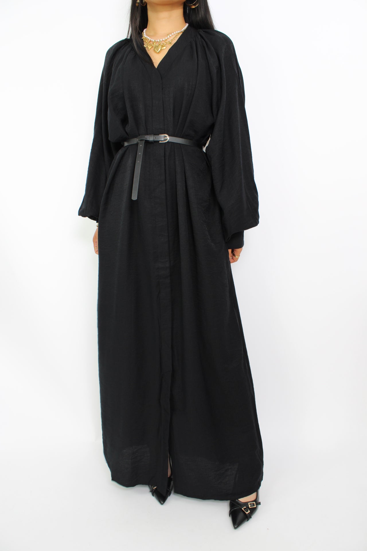 Een modest jurk in zwart, met een losse pasvorm, lange mouwen, een hoge halslijn en een bijpassende ceintuur. Gemaakt van ademende, niet-doorzichtige stof voor comfort en stijl.