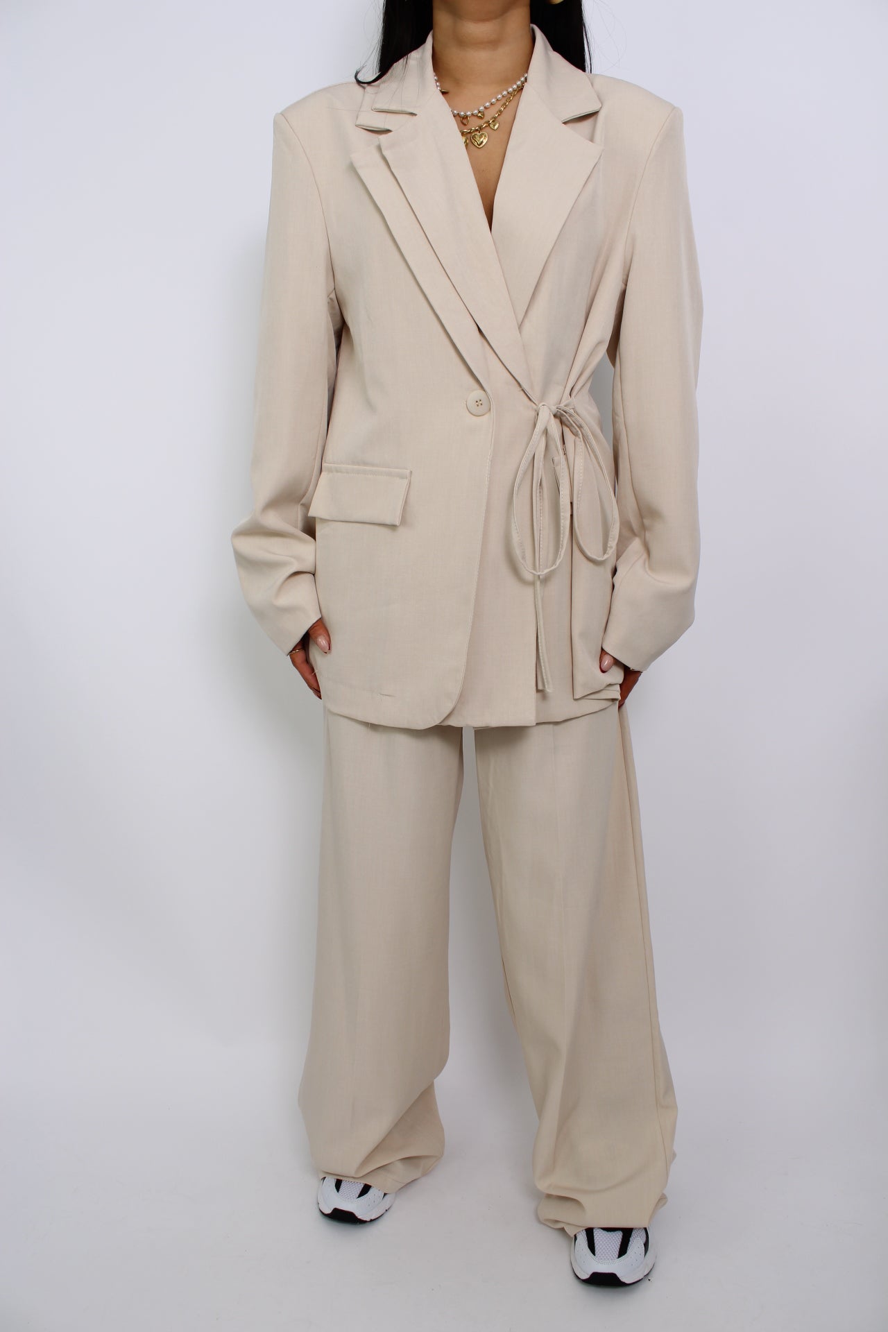 Een twee-delige set bestaande uit een pantalon en een blazer, beide met een moderne pasvorm. De set heeft een elegante uitstraling en is perfect voor een formele of zakelijke look.