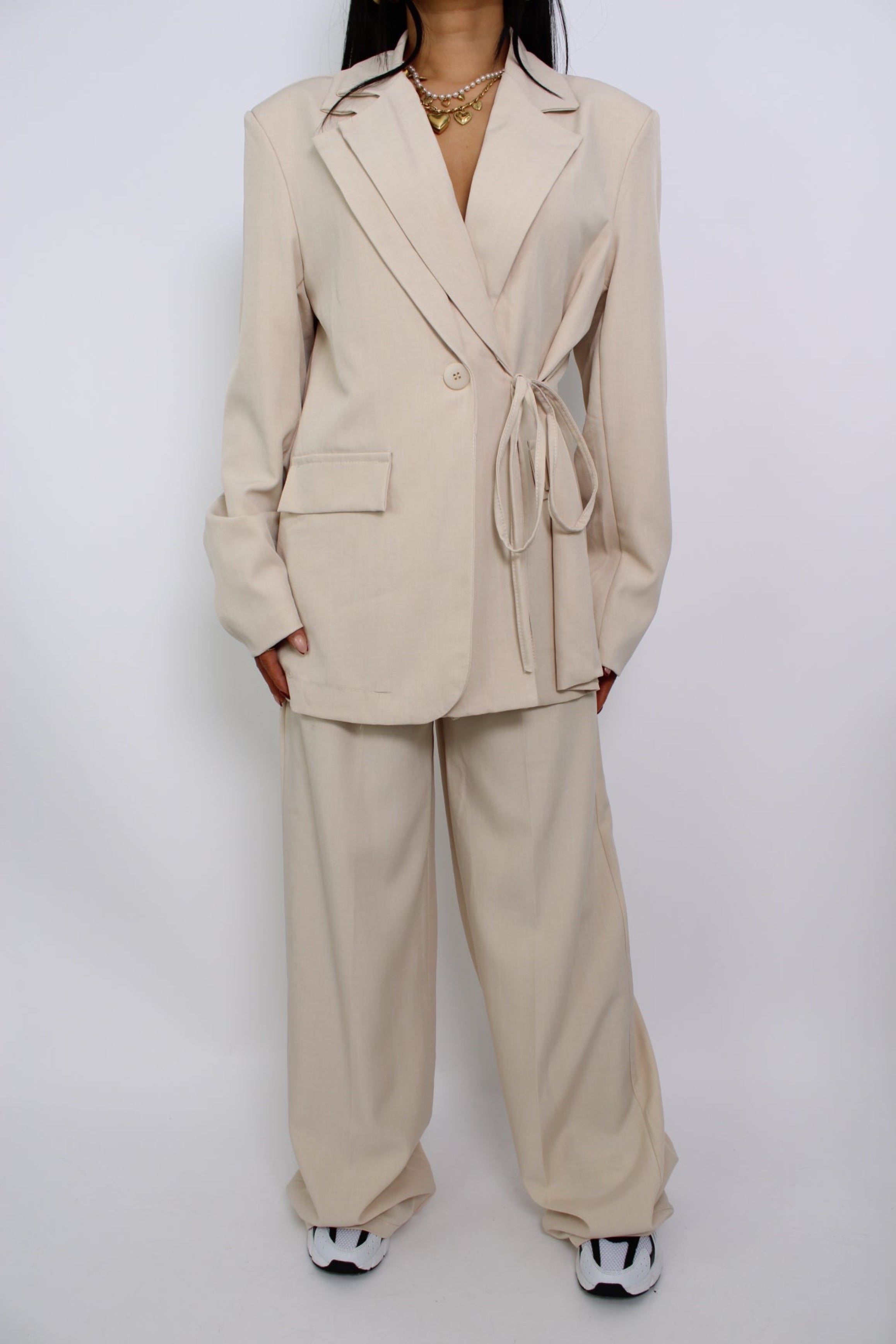Een twee-delige set bestaande uit een pantalon en een blazer, beide met een moderne pasvorm. De set heeft een elegante uitstraling en is perfect voor een formele of zakelijke look.