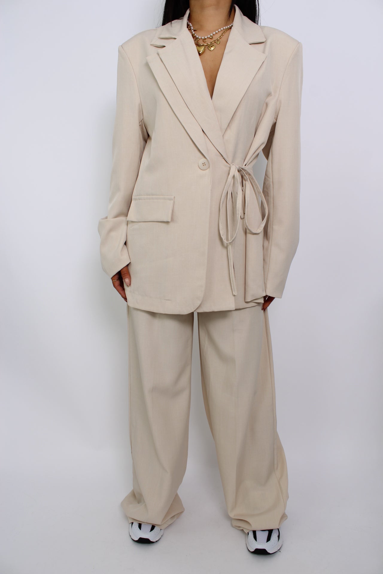 Een twee-delige set bestaande uit een pantalon en een blazer, beide met een moderne pasvorm. De set heeft een elegante uitstraling en is perfect voor een formele of zakelijke look.