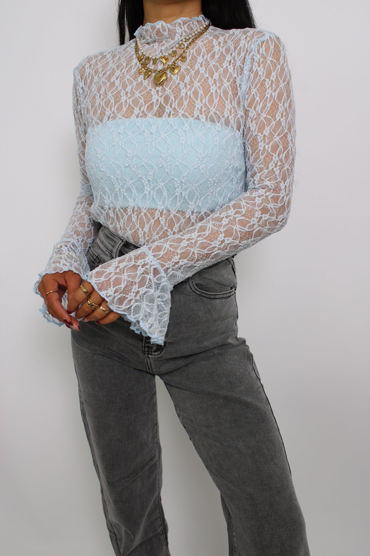 Een elegante kanten top met flare mouwen, een losse pasvorm en een verfijnde uitstraling. De top heeft een ronde halslijn en een delicate, doorzichtige stof voor een vrouwelijke look."