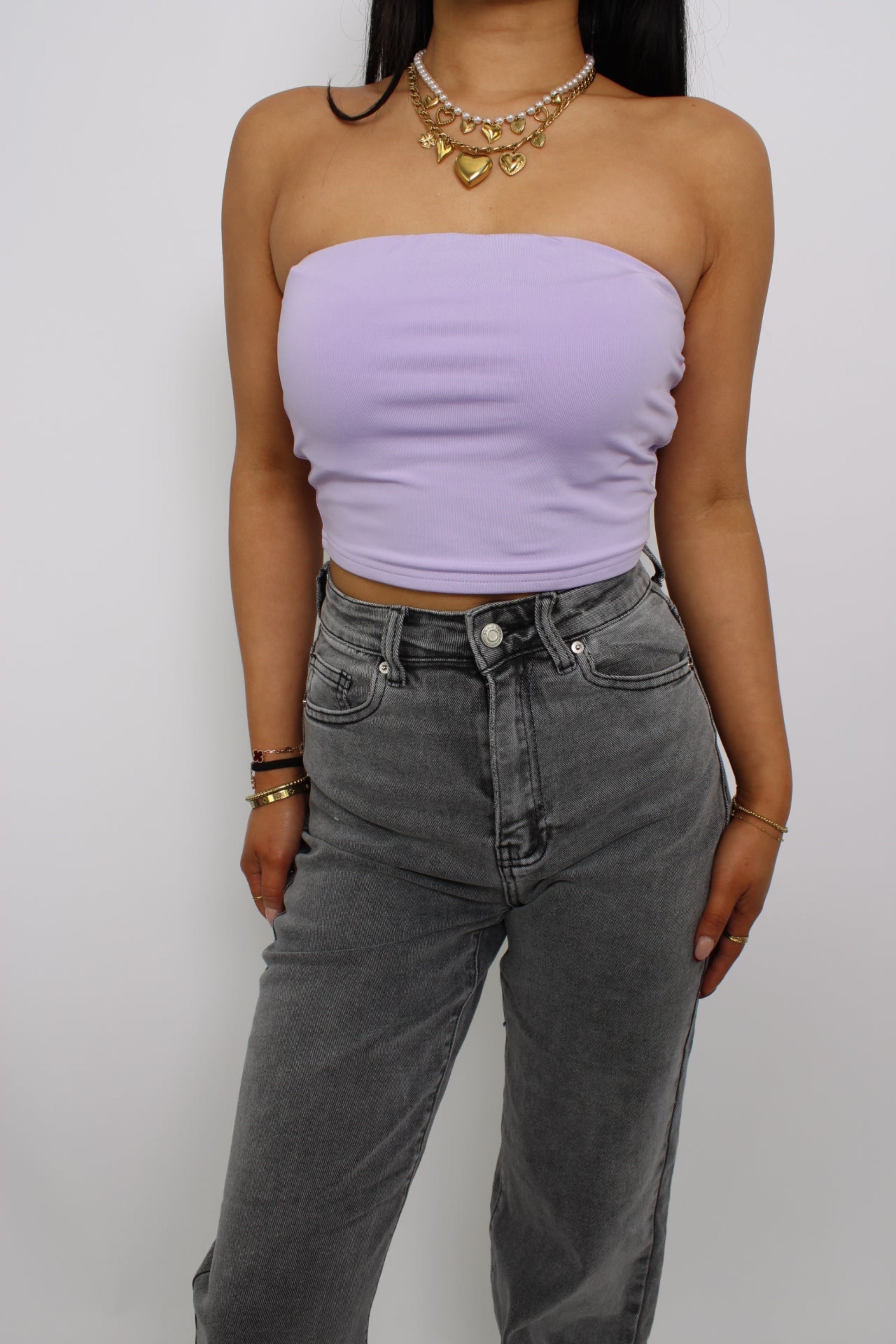 Een strapless tube top, gemaakt van elastische stof voor een comfortabele, nauwsluitende pasvorm. Het ontwerp heeft geen bandjes en valt net boven de taille voor een trendy en casual look."